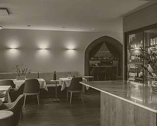 Modern eingerichtetes Restaurant mit Tischen, Stühlen, Bar und Weinregal