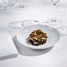 Piatto gourmet finemente preparato con funghi ed erbe su piatto bianco con bicchieri e tovagliolo