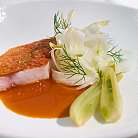 Pesce fritto con pelle croccante, salsa rossa e erbe fresche su piatto bianco