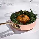 Pasticcini in pentola di rame con erbe fresche su tavolo bianco con bicchieri